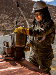 A worker in protective gear handles equipment at an industrial site.