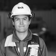Man in hard hat and safety vest smiling, monochrome photo.