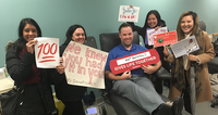 Group at a blood donation center holding supportive signs, donating blood.