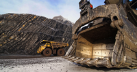 Large mining vehicles at a site with rocky terrain in the background.