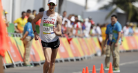 Runner in Canada jersey competing in a race with cheering crowd in the background.
