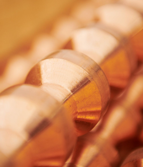 Close-up of stacked copper rods with a warm, golden glow.