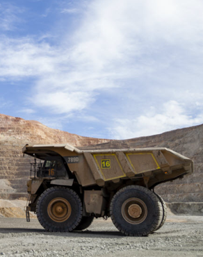 Huge dump truck in a mining area under a partly cloudy sky.
