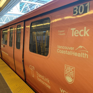 Orange subway car with various sponsor logos at a station platform.