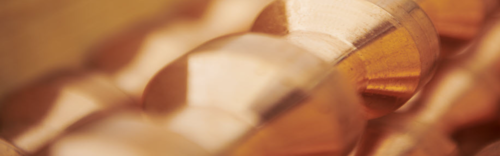 Close-up of polished copper pieces with a warm, metallic sheen and smooth surfaces.