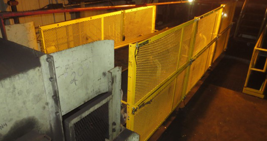 Industrial area with yellow safety barriers and machinery under artificial lighting.