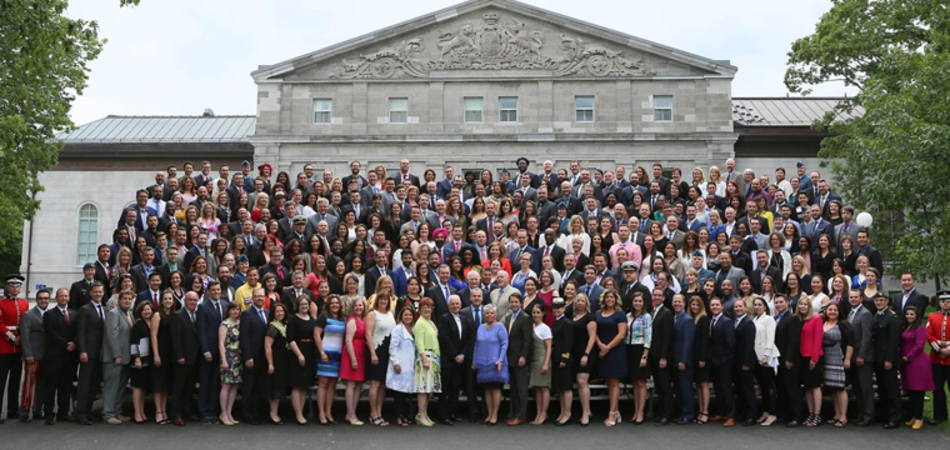 A large group of people standing in front of a historic building, posing for a group photo.